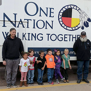 group picture of students and teachers in front of the sign One Nation Walking Together