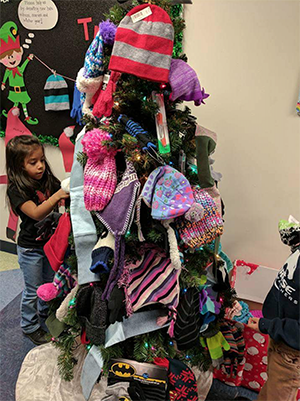 a child putting hats on a christmas tree for her pbl project