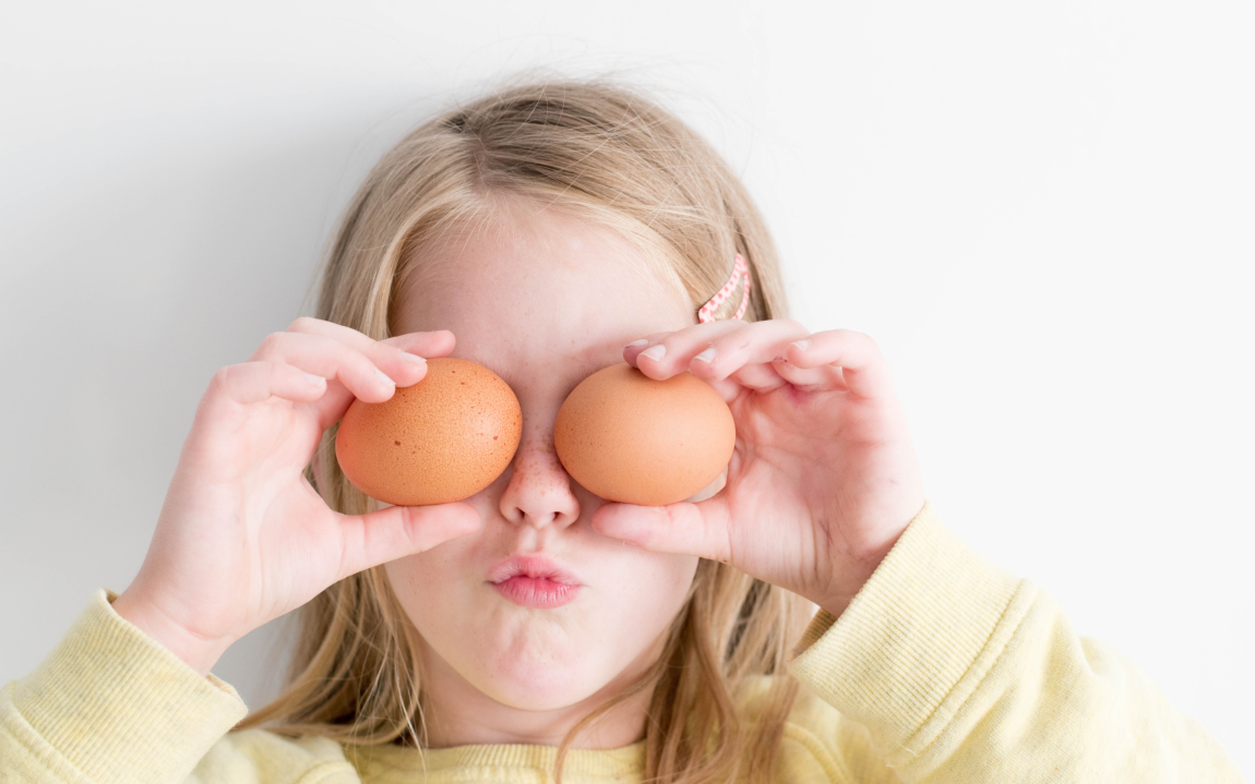 girl holding eggs to her face like eyes